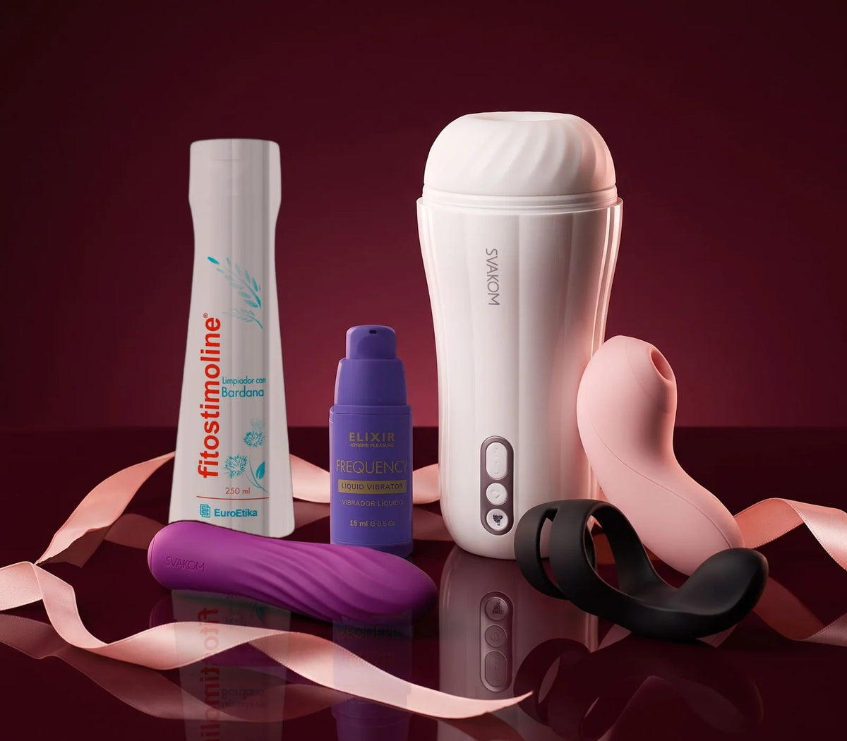 Limpiador íntimo Fitostimoline, lubricante Frequency de Elixir y juguetes Svakom (succionador Pulse Lite Neo, bala Tulip, anillo Benedict y masturbador Robin) con una cinta de satín rosada sobre fondo vino